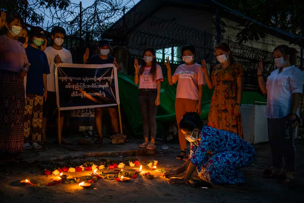 A woman lights a candle while others flash the three-fingered sign of resistance during a candlelight vigil to remember those who died in the military junta’s violent response to anti-coup demonstrations in Yangon, Myanmar (AP)