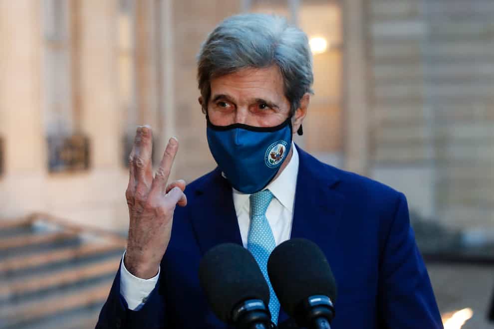 John Kerry gestures by holding up three fingers on his right hand