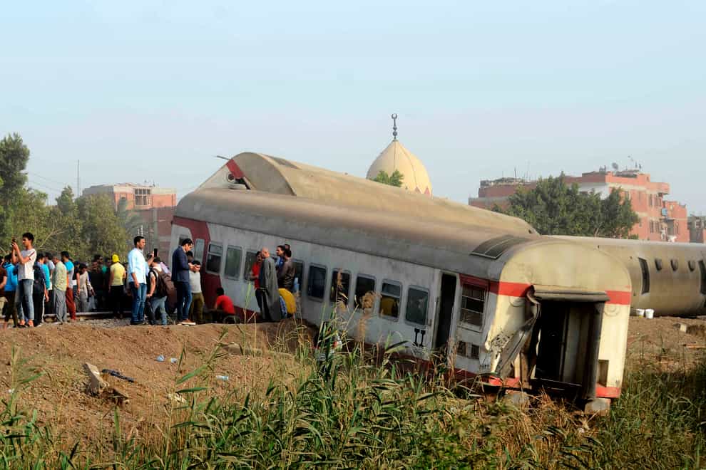 People gather at the site where a passenger train derailed injuring at least 100 people, near Banha, Qalyubia province, Egypt (Tarek Wagih/AP)