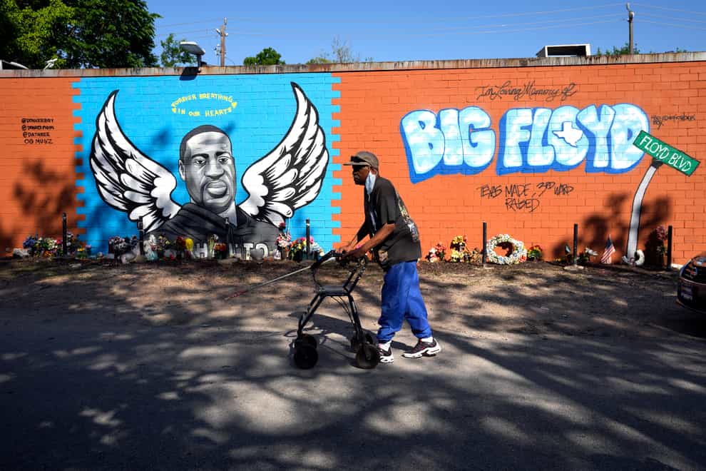 A man walks past a mural in the Houston neighbourhood where George Floyd grew up