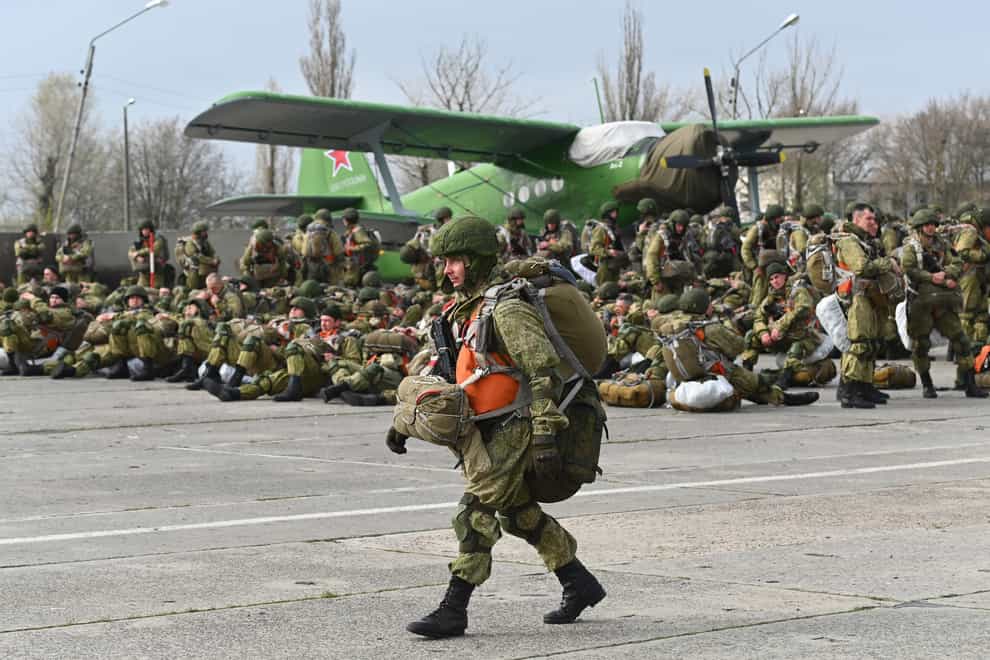 A Russian paratrooper walks as others wait to be loaded into a plane for airborne drills during manoeuvres in Taganrog, Russia