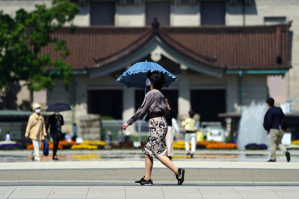 A woman wearing a protective mask to help curb the spread of the coronavirus walks at a park in Tokyo