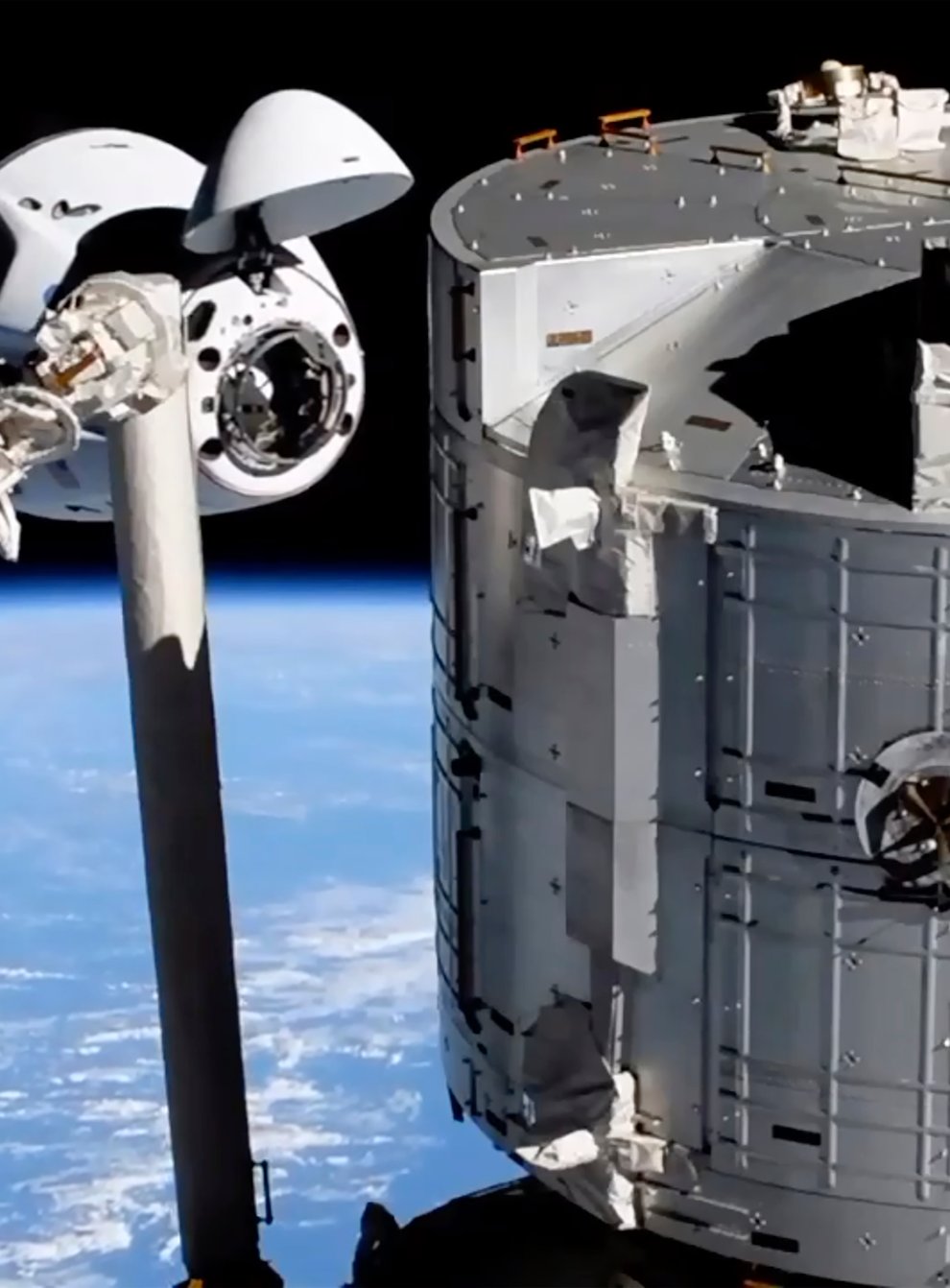 The SpaceX Crew Dragon spacecraft, left, approaches the International Space Station