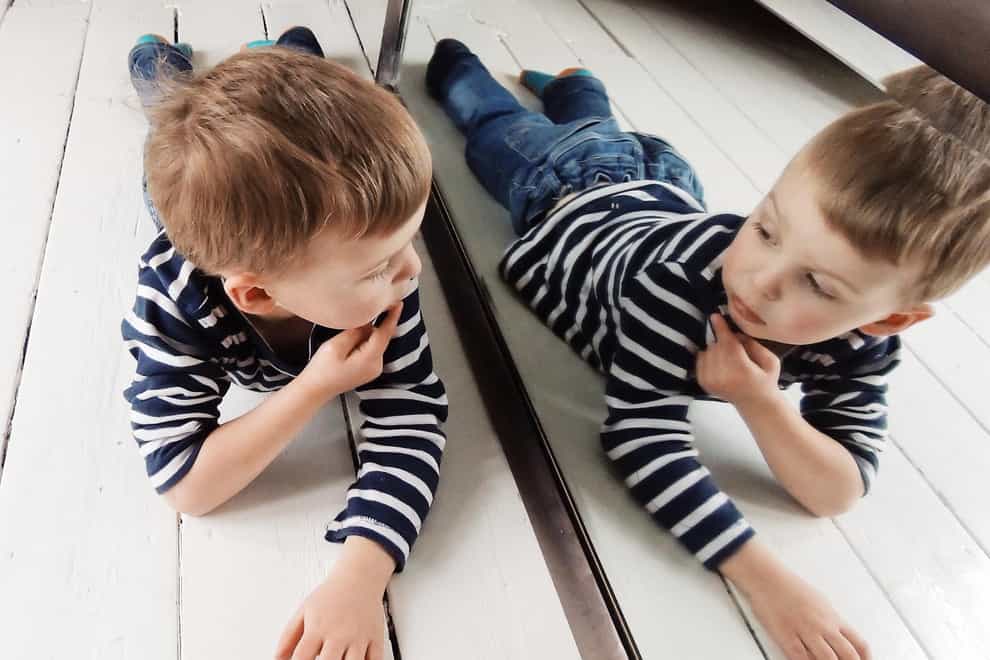 Portrait of a Boy lying on the floor looking at himself in the mirror