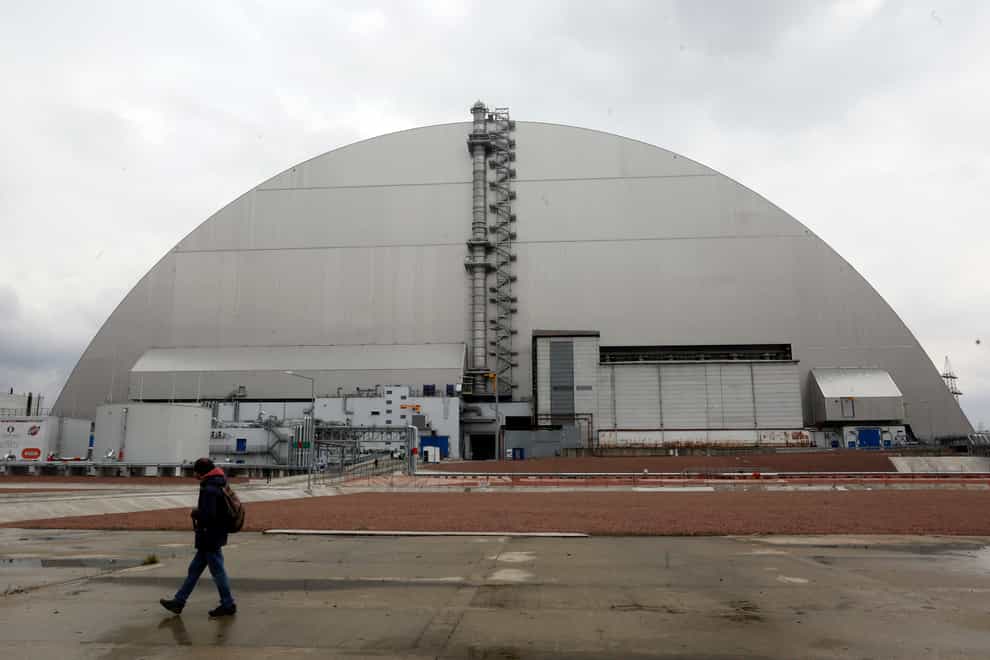 A man walks past a shelter covering the exploded reactor at the Chernobyl nuclear plant