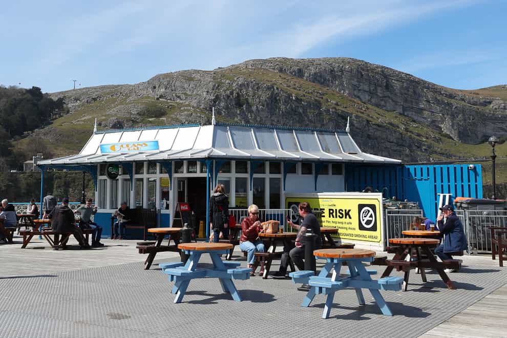 People sit outside a bar in Llandudno, Wales, where lockdown restrictions have eased