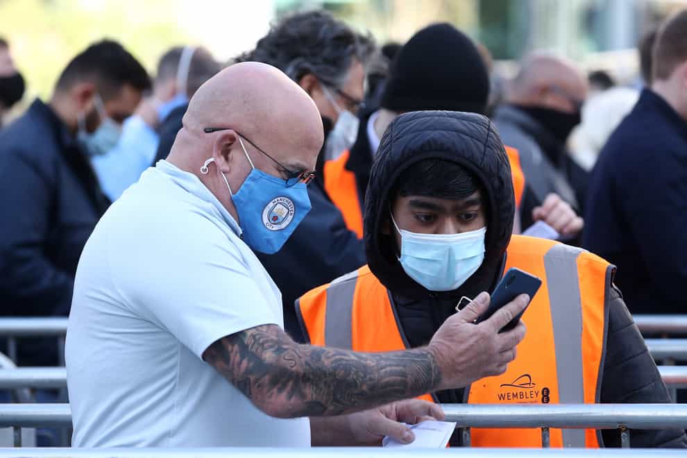 A Manchester City fan shows a Covid-19 test result to a steward outside the Wembley stadium ahead of the Carabao Cup Final (Gareth Fuller/PA)