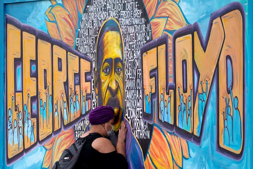 A woman pays her respects to George Floyd at a mural in Minneapolis