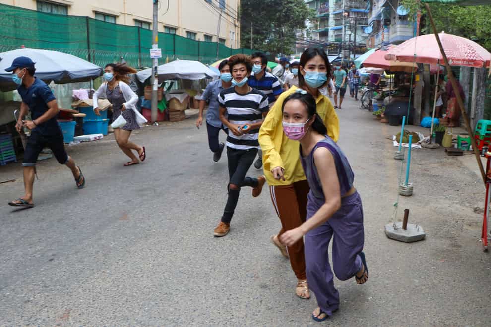 Anti-coup protesters run after seeing police and soldiers arrive to disperse their demonstration in Yangon, Myanmar