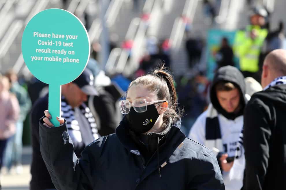 A steward in a mask outside Wembley stadium asks fans for Covid-19 test results as a condition of entry ahead of the Carabao Cup Final (Gareth Fuller/PA)