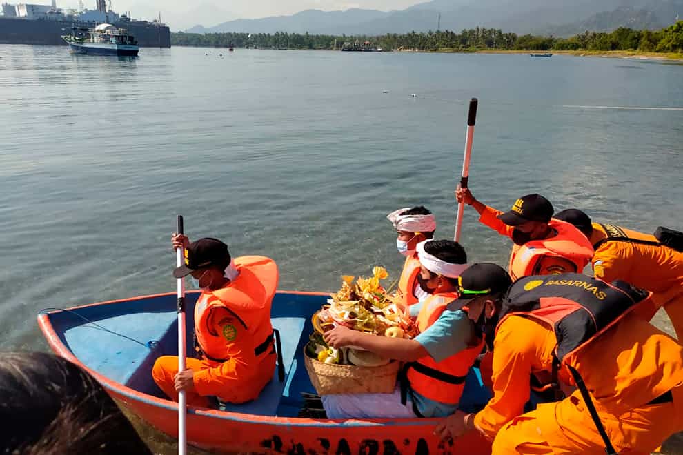National Search and Rescue Agency personnel help relatives of Captain Gede Kartika, one of the junior officers of Indonesian Navy submarine KRI Nanggala that sank on April 21, to carry offerings to the sea during a prayer in Celukan Bawang, Bali (Al Rizki/AP)