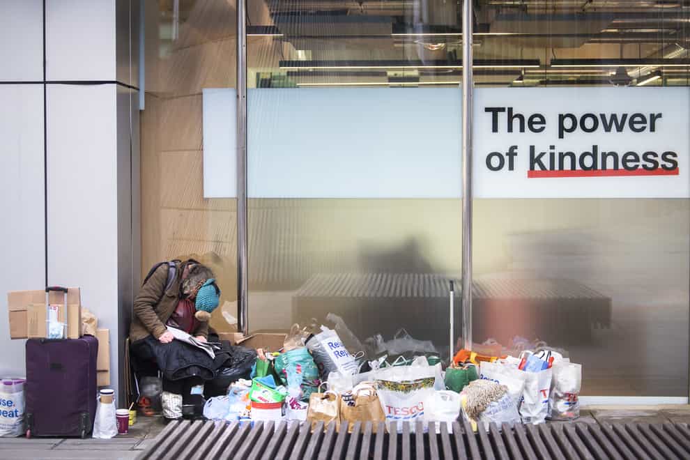 A homeless person sits in a window in the City of London. (Victoria Jones/PA)