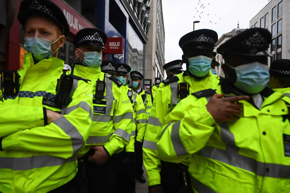 Police officers observe an anti-lockdown protest in London’s Oxford Street (PA)