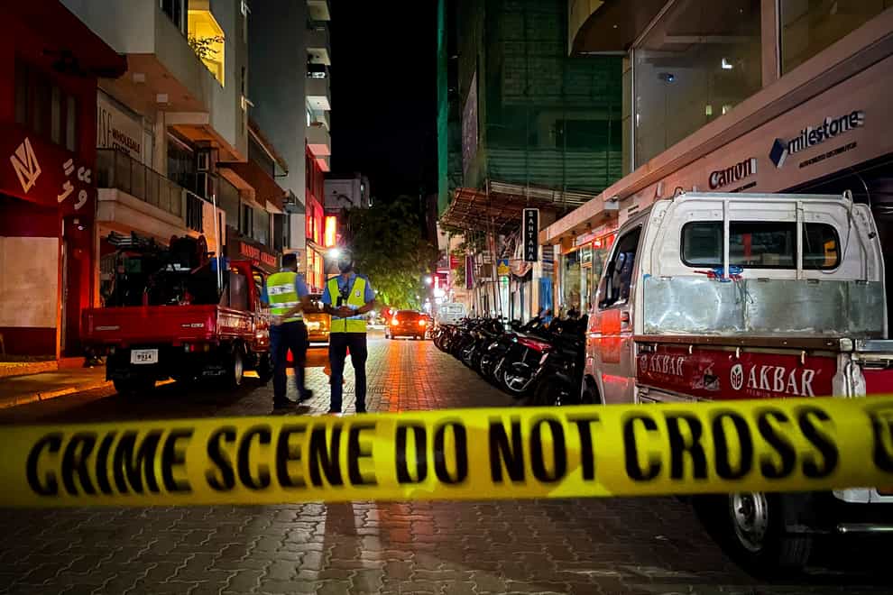 Maldivian police officers stand behind police tape