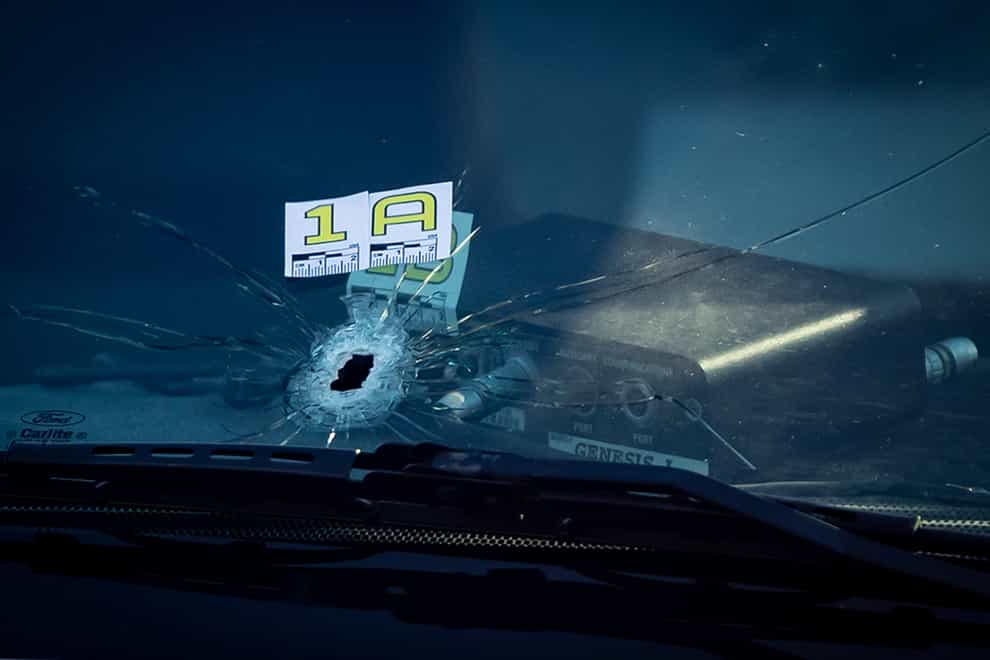 A bullet hole is seen in the windshield of a police vehicle