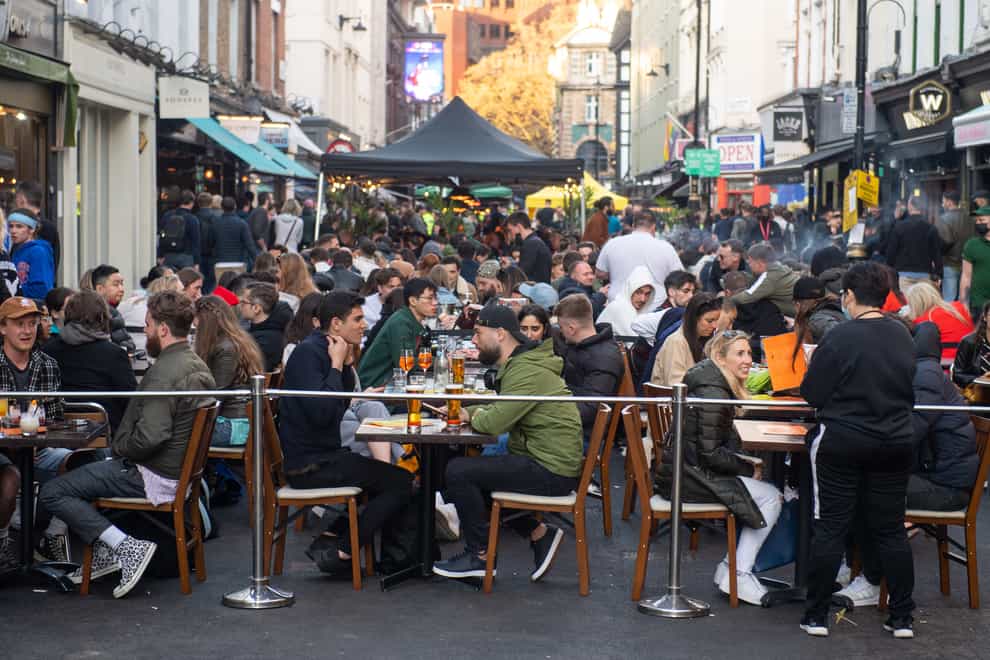 People eat and drink at outside tables in Soho, central London