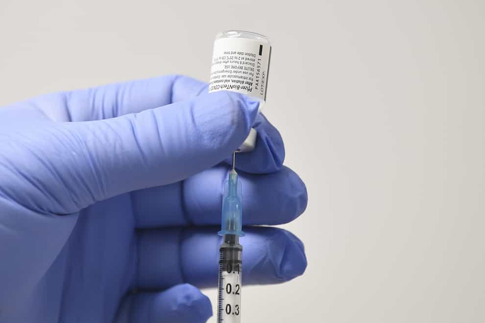 A member of staff uses a needle and a phial of Pfizer/BioNTech Covid-19 vaccine