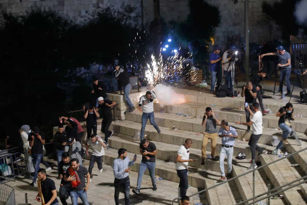 Palestinians run from stun grenades fired by Israeli police officers during clashes at Damascus Gate just outside Jerusalem’s Old City