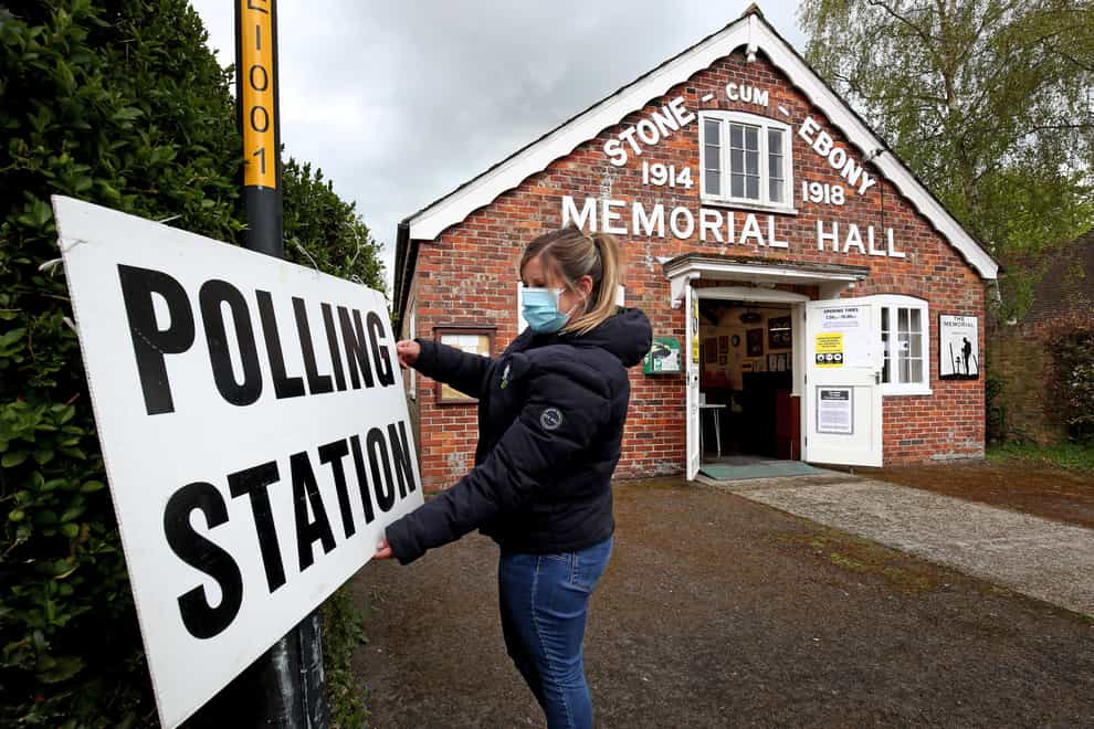 A poll clerk adjusts the sign outside Stone-cum-Ebony polling station near Ashford in Kent