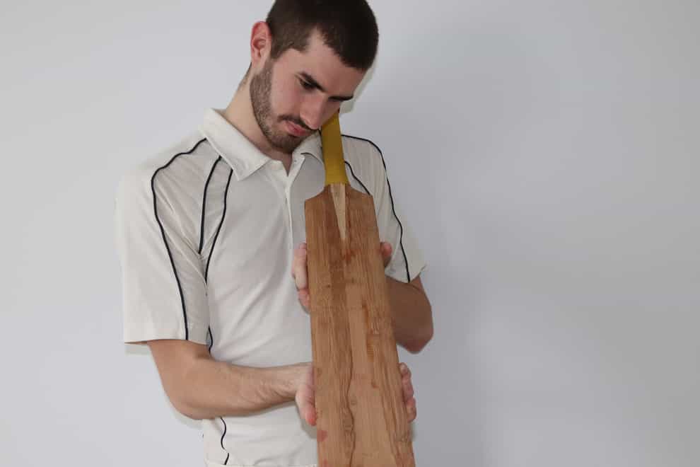 A cricketer holding a bat made from bamboo