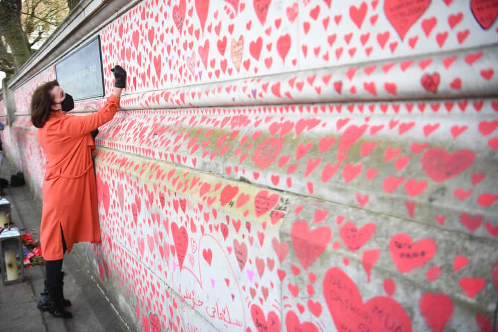 Fran Hall, who lost her husband to coronavirus, takes part in the final stages of painting approximately 150,000 hearts on the Covid memorial wall on the Embankment in London (Victoria Jones/PA)