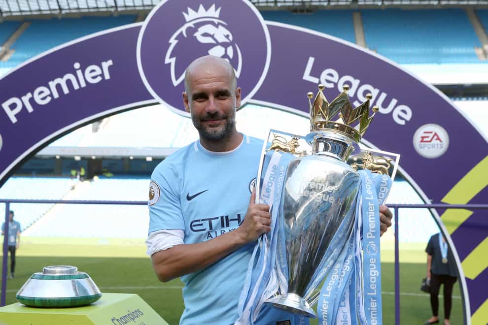 Manchester City manager Pep Guardiola celebrates with the Premier League trophy.