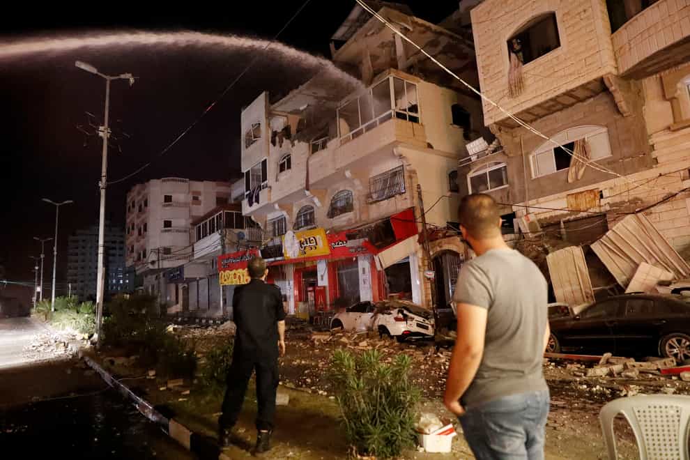 Firefighters extinguish burning apartment buildings after they were hit by Israeli airstrikes, in Gaza City