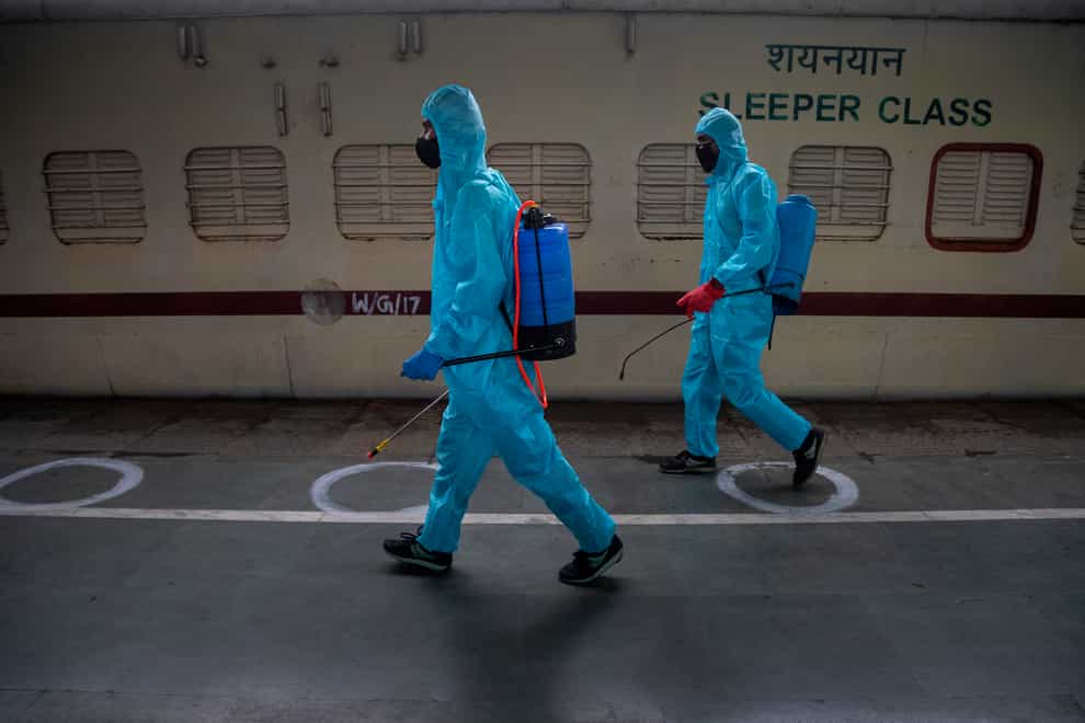 Health workers in personal protective equipment sanitise a train prepared as a Covid-19 care centre at a railway station in Gauhati, India