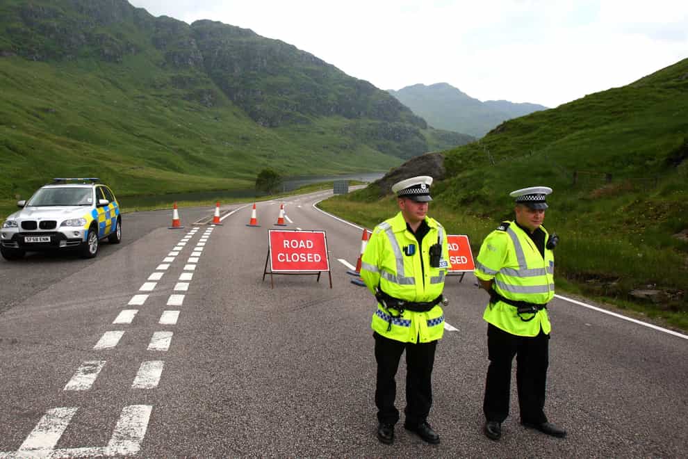 Police officers stand on a rural road
