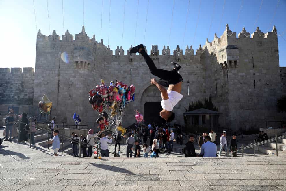 A Palestinian youth performs a back flip at the Damascus Gate to the Old City of Jerusalem as people gather for Eid al-Fitr, marking the end of the Muslim holy month of Ramadan