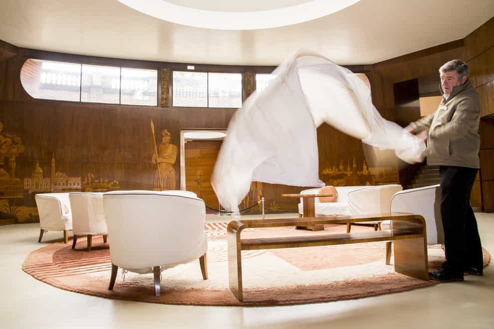 Paul Fretwell removes dust sheets from the furniture in the Grand Entrance at Eltham Palace in London
