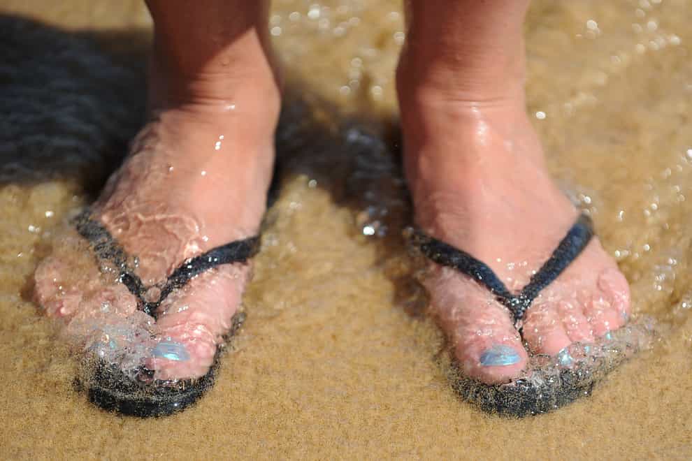 A woman wearing flipflops on a beach in Portugal