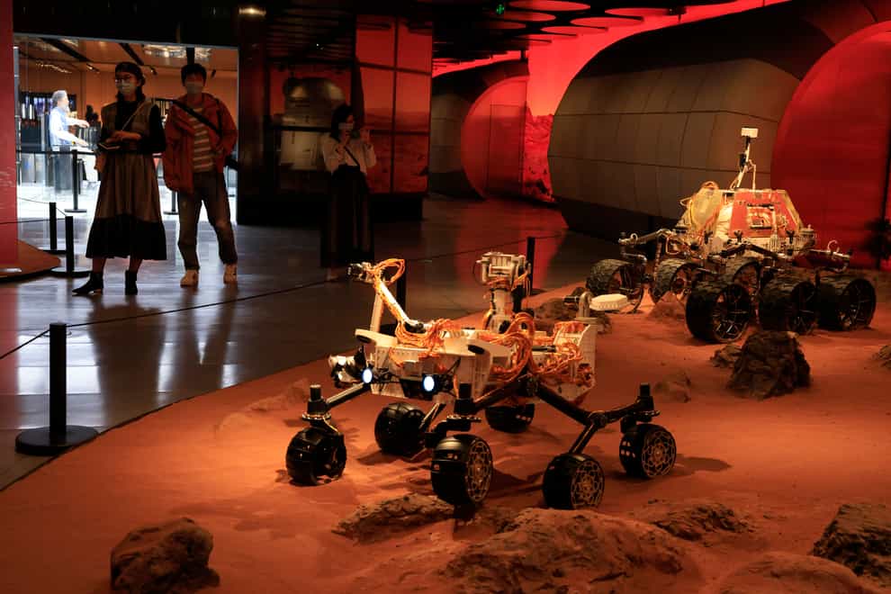 Visitors pass by an exhibition depicting rovers on Mars