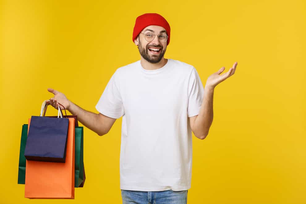 Bearded man with shopping bags with happy feeling isolated on yellow bacground