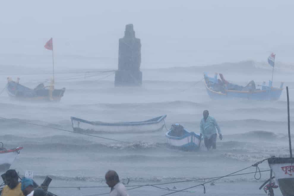 A fisherman waits for help as he tries to move a boat to safer ground
