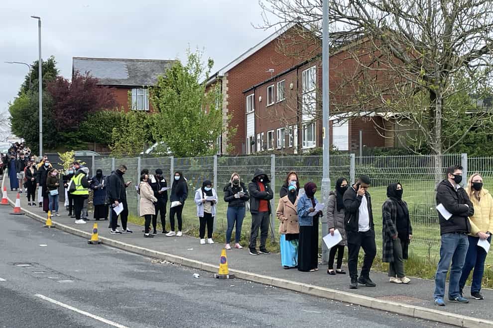 People queue for the vaccination centre at the Essa Academy in Bolton