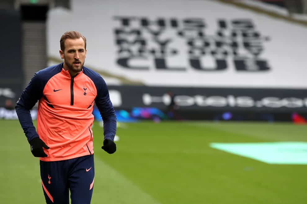 Harry Kane warms up in front of a Tottenham banner reading 'This is my club, my one and only club'
