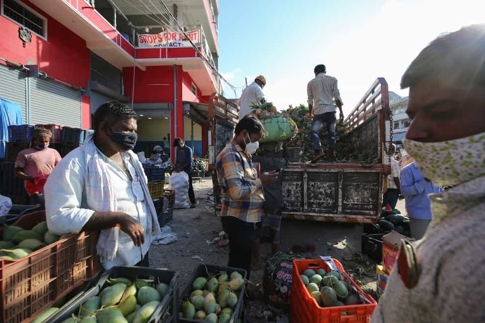 Workers unload fruits at a market during the relaxation hours of a lockdown to curb the spread of Covid-19 in Bengaluru, India (Aljaz Rahi/AP)