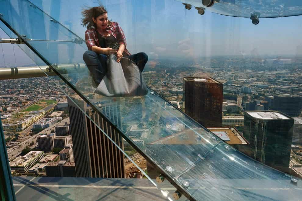 A member of the media rides down a glass slide during a media preview at the US Bank Tower building in Los Angeles