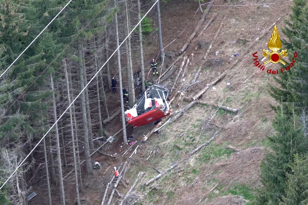Rescuers work by the wreckage of a cable car after it collapsed near the summit of the Stresa-Mottarone line in the Piedmont region, northern Italy