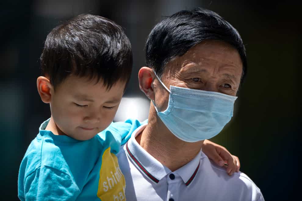 A man wearing a face mask carries a boy