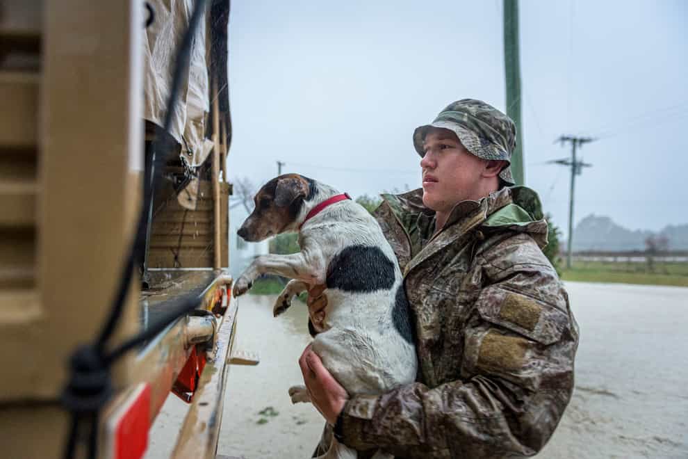 A member of the New Zealand Defence Force rescues a dog from floods as they assist a family with their evacuation near Ashburton in New Zealand’s South Island
