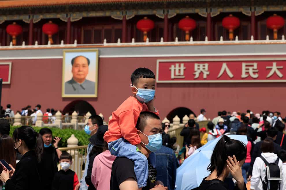 A man and child wearing masks visit Tiananmen Gate near the portrait of Mao Zedong in Beijing, China