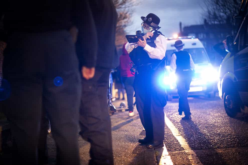 A police officer uses her radio during a stop and search (Victoria Jones/PA)