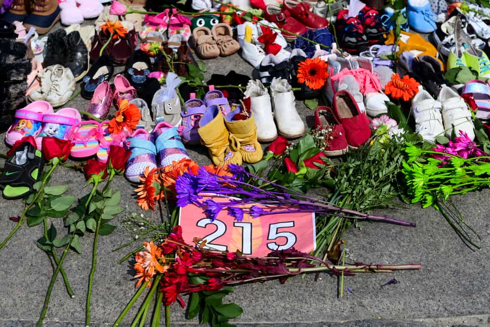 Flowers, children’s shoes and other items at a memorial at the Eternal flame on Parliament Hill in Ottawa