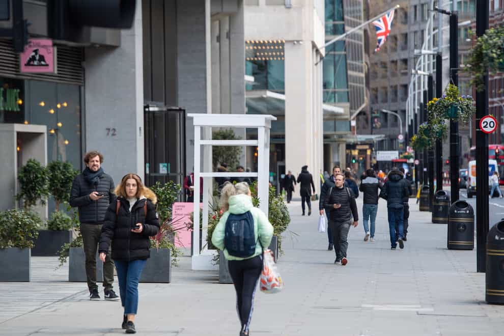 People pass shops and offices on a street in central London