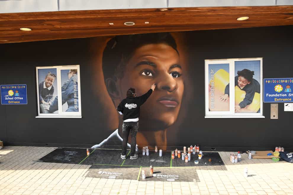 Josh from street artists MurWalls paints a mural of footballer Marcus Rashford on the wall of Gainsborough Primary School