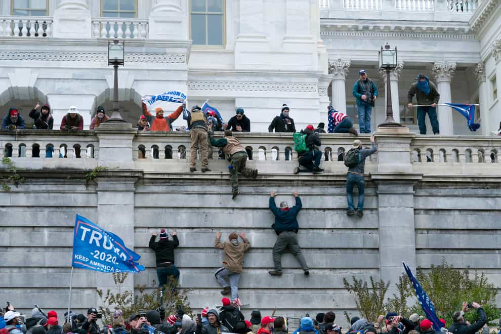 Violent insurrectionists loyal to President Donald Trump scale the west wall of the the US Capitol in Washington (Jose Luis Magana/AP)