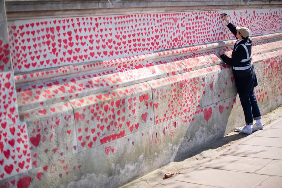 A volunteer adds hearts to the Covid Memorial Wall in London