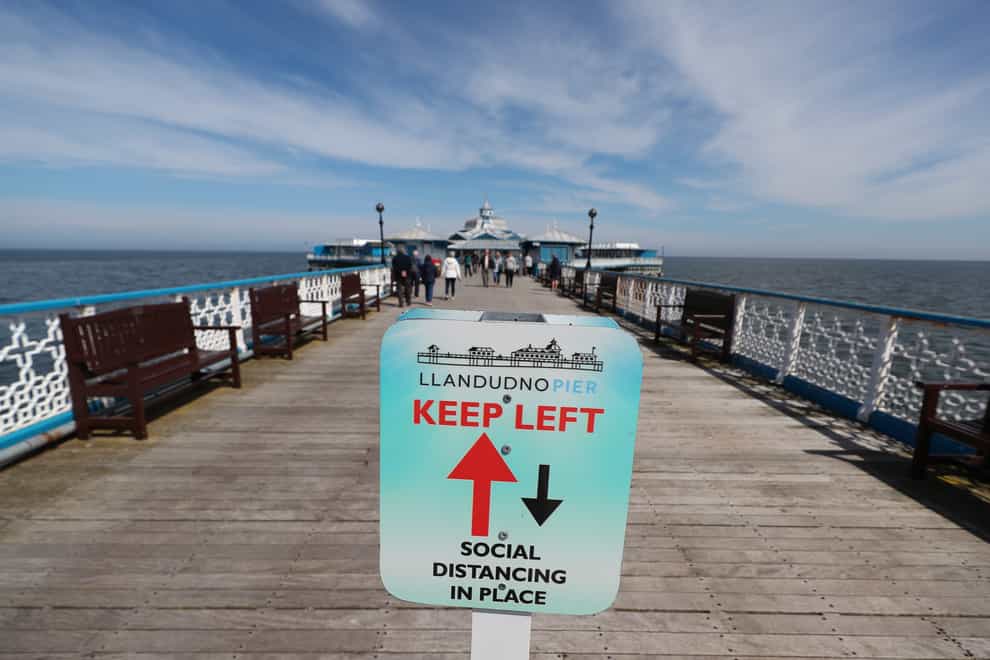 A social distancing sign on the pier in Llandudno, Wales, where lockdown restrictions have eased (Peter Byrne/PA)